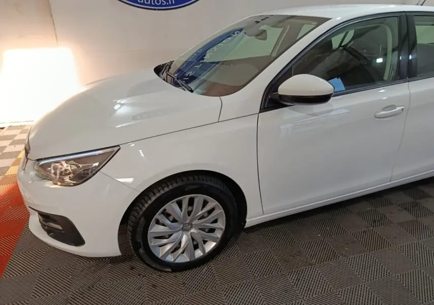 Vue 3/4 avant côté gauche d'une Peugeot 308 blanche avec phares ellipsoïdaux et jantes alliage visibles