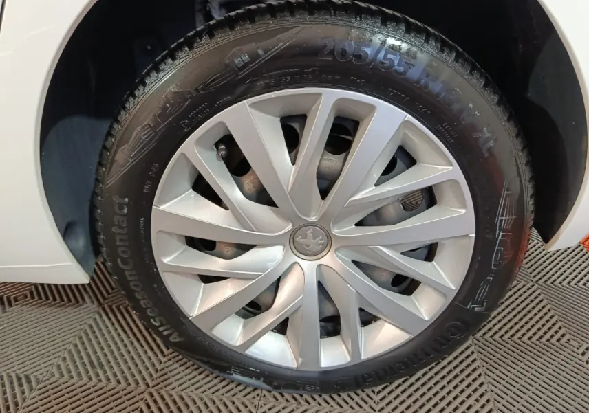 Gros plan sur la roue avant gauche blanche d'une Peugeot 308 BlueHDi 130 S&S PREMIUM PACK avec jante argentée design.