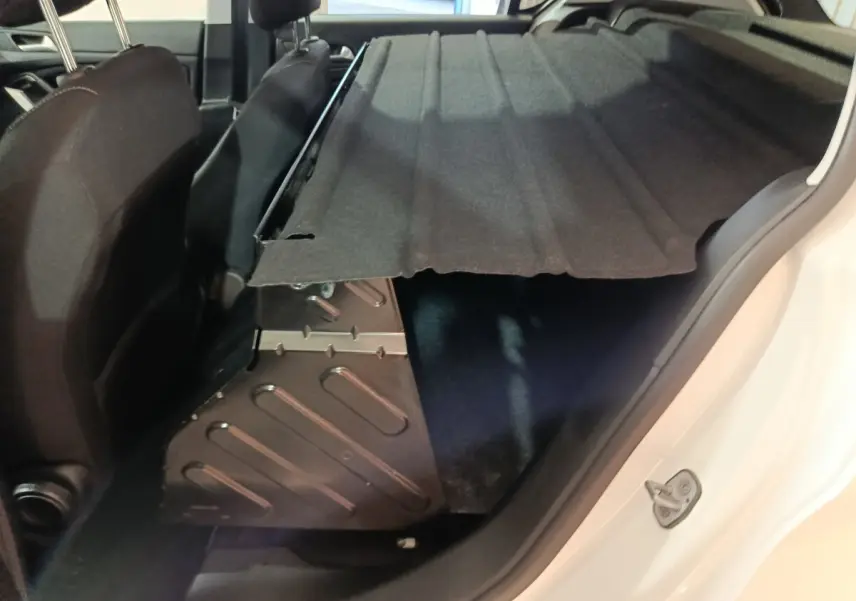 Vue intérieure côté droit du coffre de la Peugeot 308 blanc avec cache-bagages partiellement relevé.