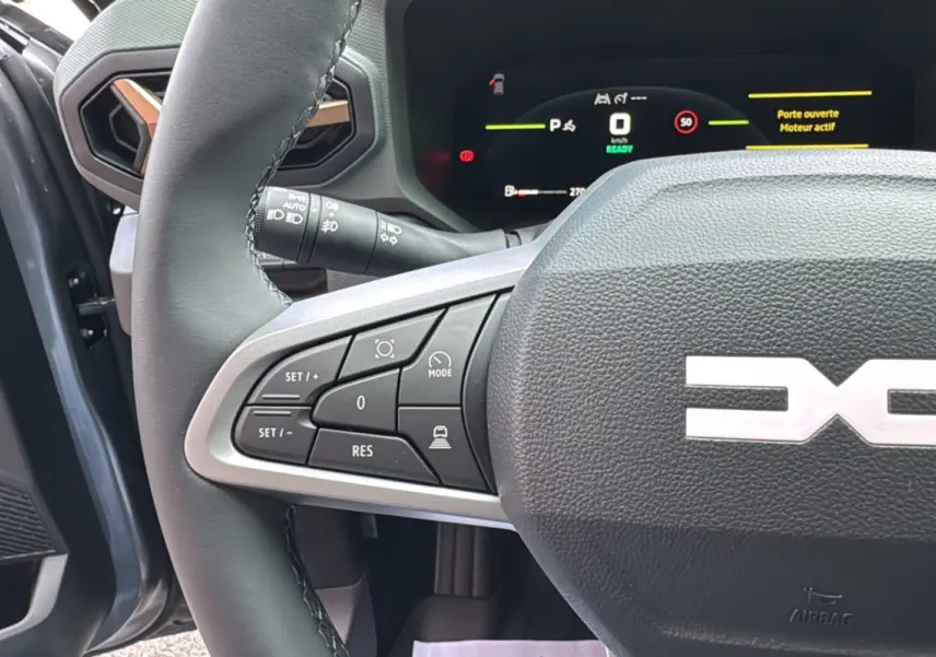 Gros plan sur le volant cuir gris schiste de la Dacia Bigster Hybrid 155 Extreme Plus avec commandes intégrées côté gauche.