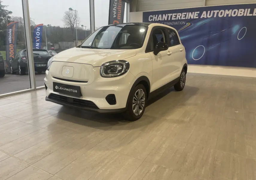 Vue 3/4 avant droite d'une Leapmotor T03 Luxury blanche électrique en showroom avec détails noirs contrastants.