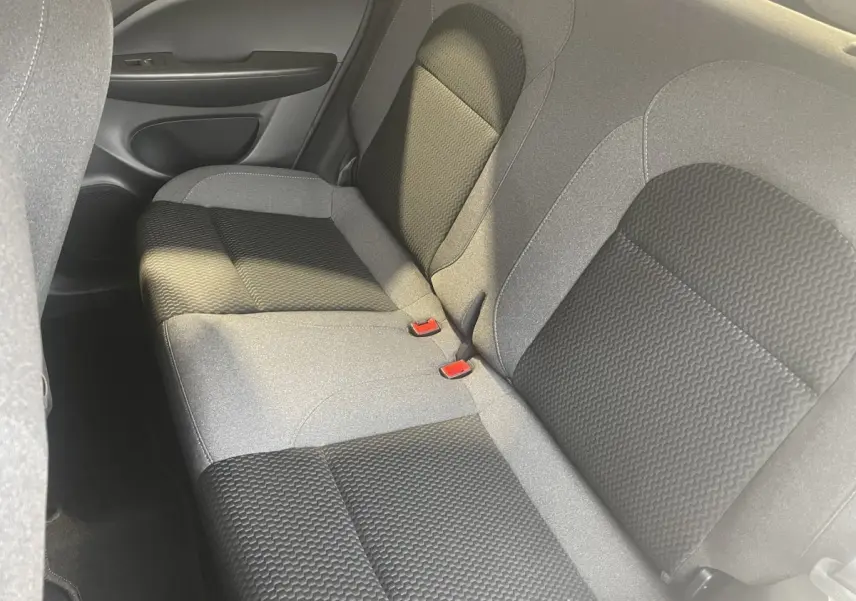 Vue rapprochée de la banquette arrière grise et noire du Leapmotor T03 Luxury 2025, montrant les ceintures rouges.