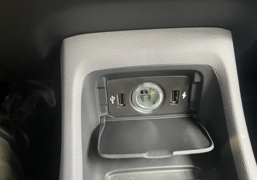 Gros plan sur la prise 12V et ports USB dans la console centrale du Leapmotor T03 Luxury blanc, intérieur sombre.