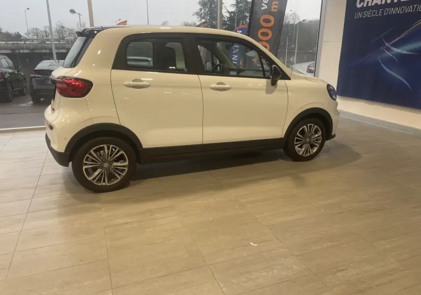 Vue de profil côté gauche d'une LEAPMOTOR T03 Luxury blanche, compacte et électrique, en intérieur showroom.