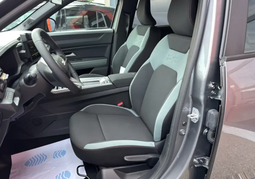 Vue intérieure côté conducteur du Dacia Bigster gris schiste, mettant en valeur les sièges bi-ton avec logo BC embossé.