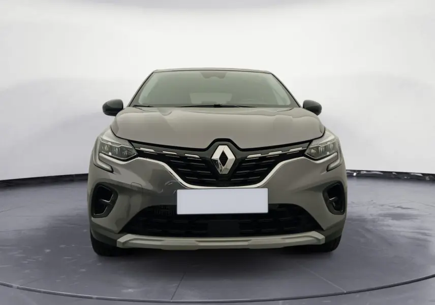 Vue frontale du Renault Captur 1.3 Mild Hybrid 140 Techno en gris Cassiopée avec toit noir, mettant en valeur sa calandre distinctive.