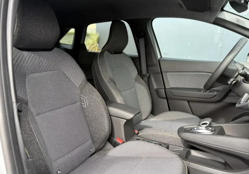 Vue intérieure côté gauche sur les sièges avant gris foncé et la console centrale du Renault Symbioz E-Tech 2025