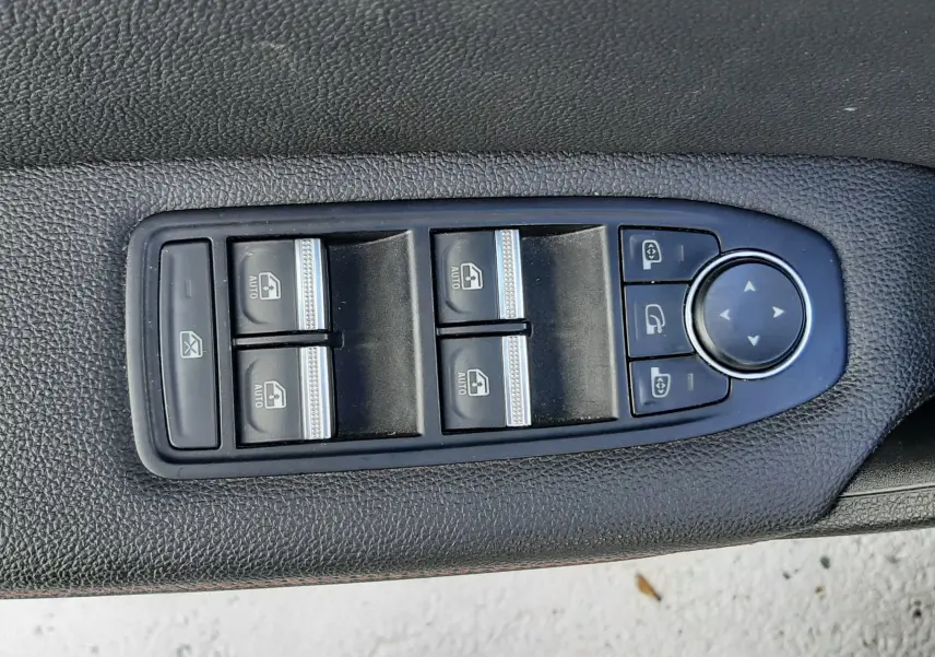 Gros plan sur les commandes des vitres électriques et rétroviseurs sur la porte côté conducteur d'un Renault Captur blanc toit noir.