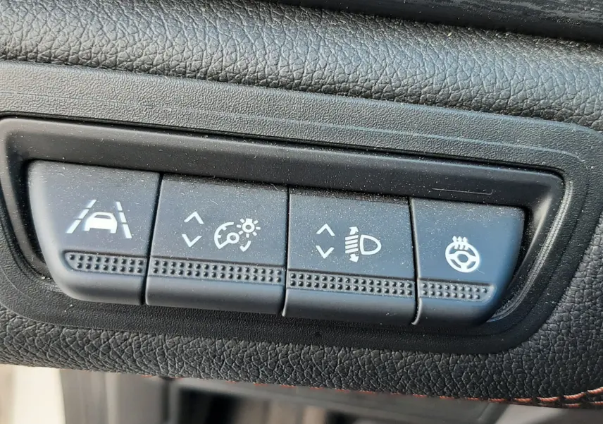 Gros plan sur les boutons de réglages d'assistance et éclairage du tableau de bord du Renault Captur blanc toit noir.