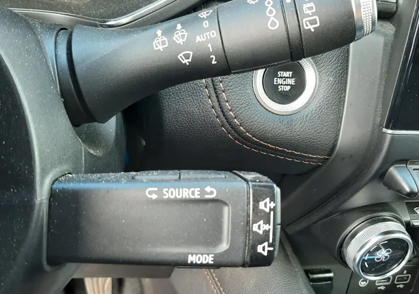 Gros plan sur les commandes au volant du Renault Captur 2020, avec bouton start/stop et coutures orange sur tableau de bord noir.