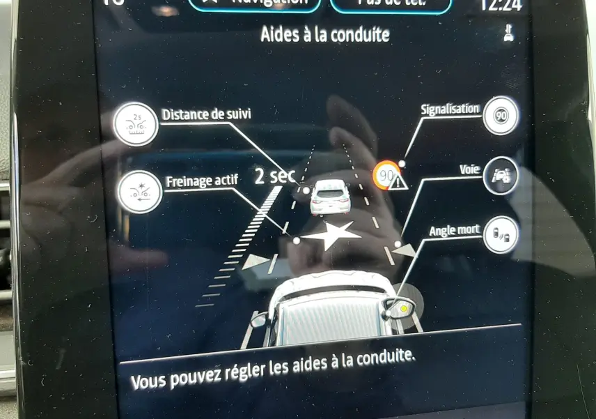 Écran tactile intérieur du Renault Captur blanc/toit noir affichant les aides à la conduite avec navigation et alertes visibles.