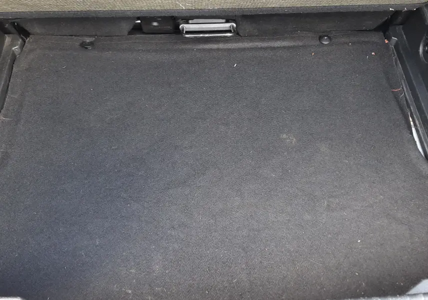 Espace de rangement sous le plancher de coffre du Renault Captur blanc toit noir, vue intérieure du compartiment vide.