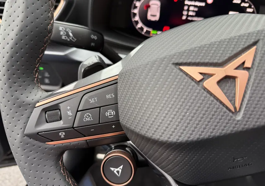 Gros plan sur le volant noir texturé avec logo CUPRA cuivre et commandes intégrées du Formentor 1.5 eHybrid 2025.