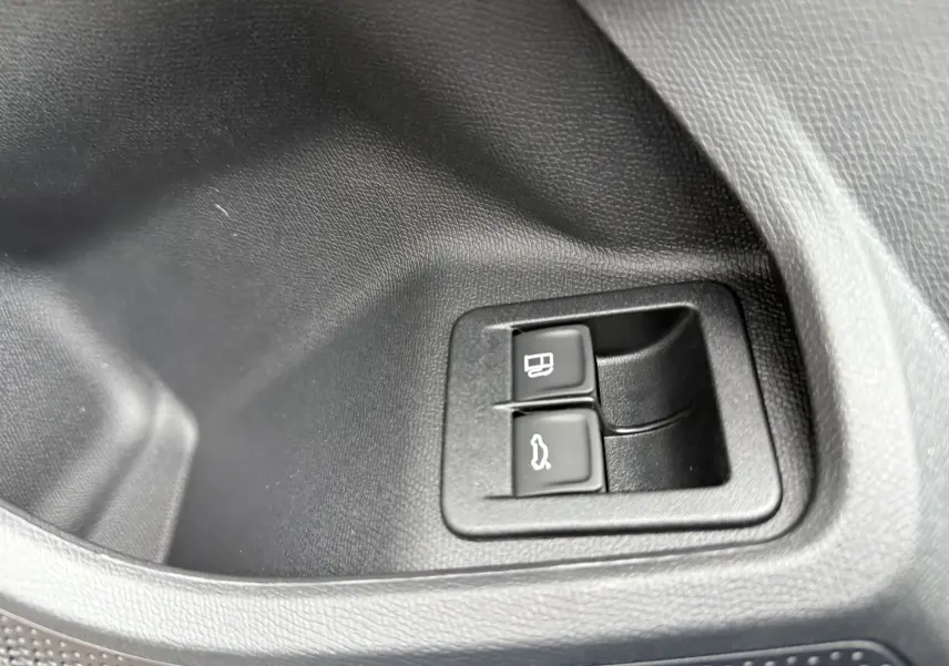 Gros plan sur les boutons d'ouverture de la trappe à carburant et du coffre dans l'habitacle noir du CUPRA Formentor.