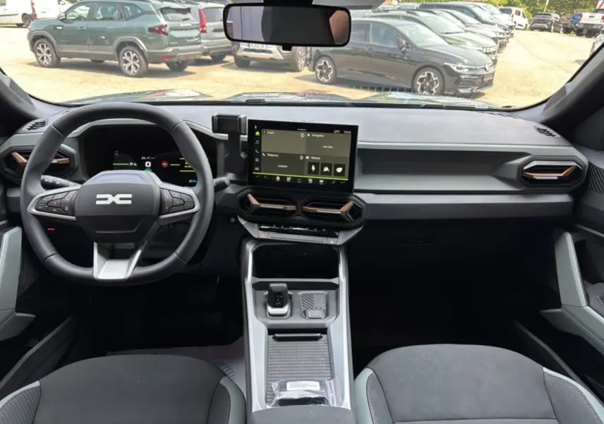 Vue intérieure avant du Dacia Bigster gris schiste, tableau de bord moderne avec écran tactile central et volant multifonction.