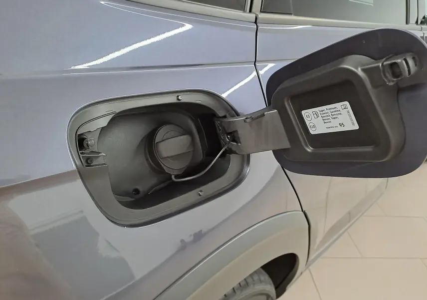 Gros plan sur la trappe à carburant ouverte côté gauche d’un Volkswagen Taigo gris cendré 2025.