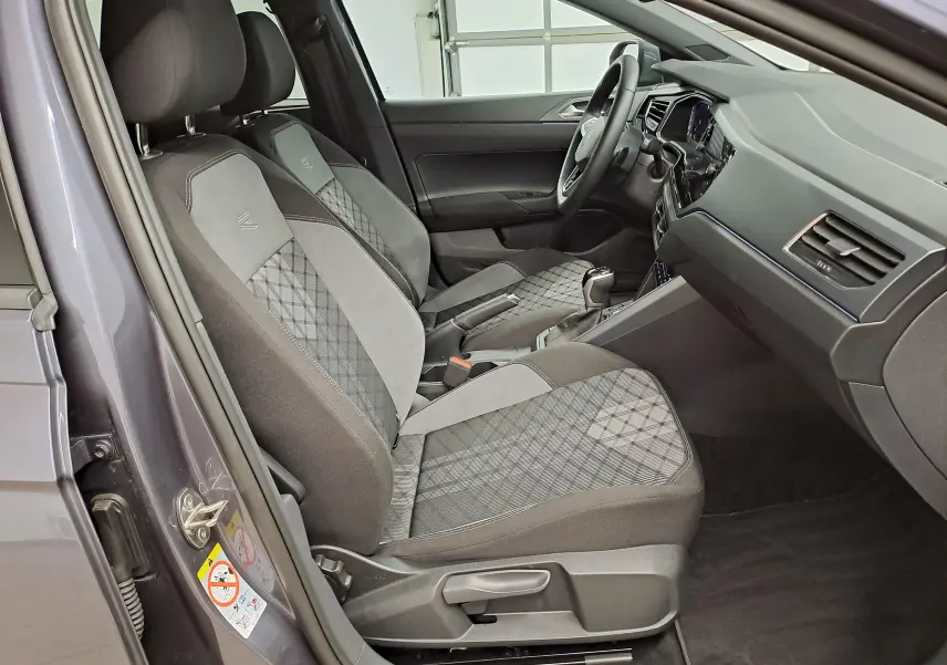 Vue intérieure côté conducteur du Volkswagen Taigo gris cendré, sièges tissu avec motifs géométriques et volant multifonction.