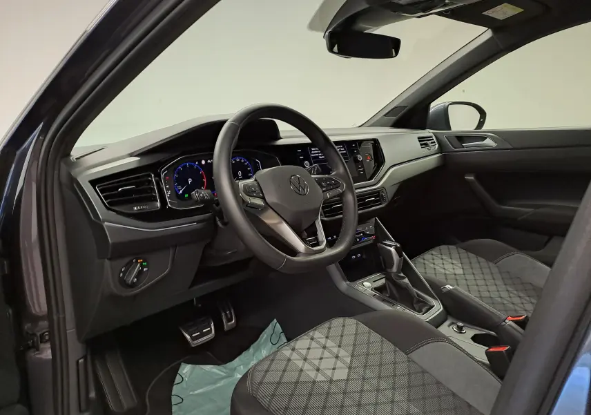 Vue intérieure côté conducteur du Volkswagen Taigo 1.0 TSI R-Line Edition avec volant multifonction et sièges tissu à motif gris.
