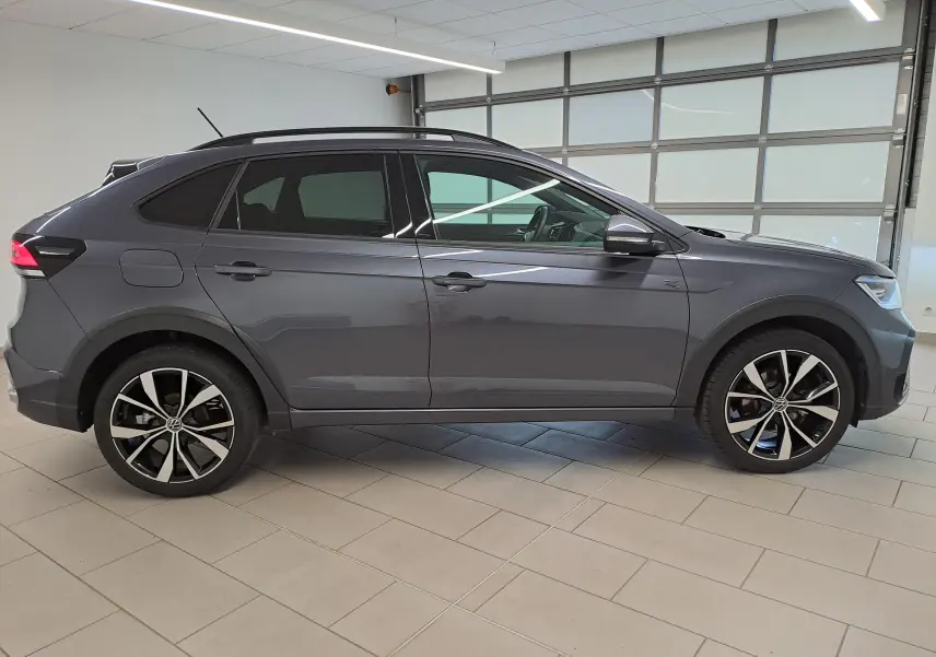 Vue de profil côté gauche du Volkswagen Taigo gris cendré avec jantes alliage 18 pouces Misano en intérieur showroom.