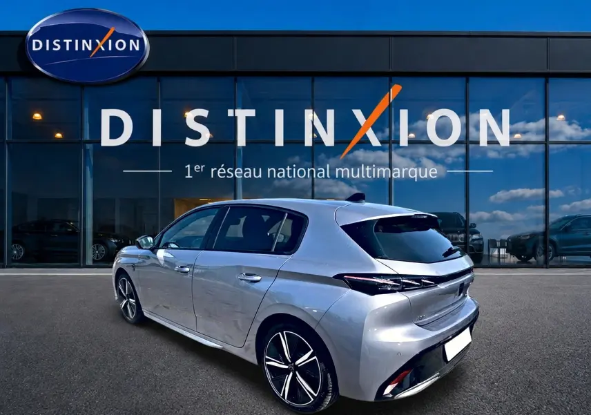 PEUGEOT 308 gris vue 3/4 arrière droit, jantes alu noires et toit avec antenne requin, devant vitrine Distinxion.