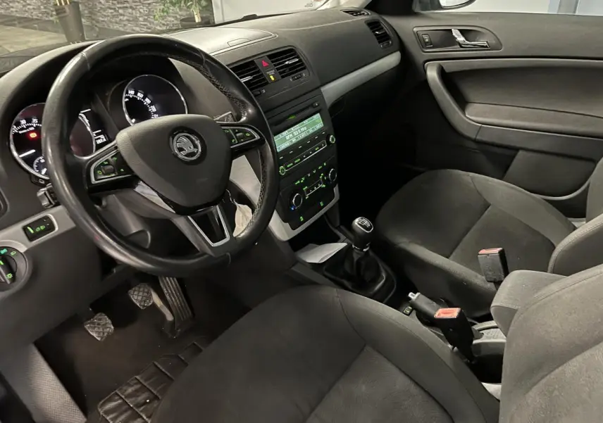 Intérieur noir du Skoda Yeti 2015 vu côté conducteur, volant cuir multifonctions et boîte manuelle visible.