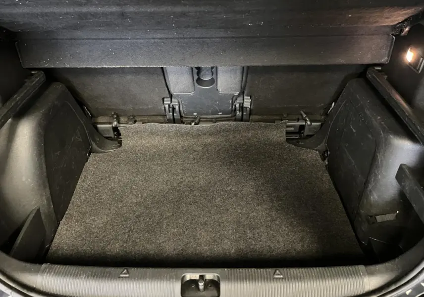 Coffre spacieux du Skoda Yeti 2015 vu de face, avec tapis gris et éclairage intérieur à droite.