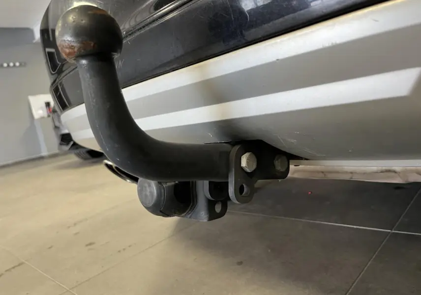 Gros plan sur l'attelage noir fixé au pare-chocs arrière gris clair d'un Skoda Yeti noir.