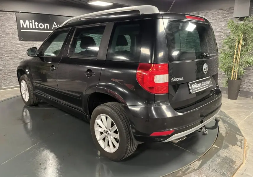 Vue 3/4 arrière droite d'un Skoda Yeti noir avec attelage et jantes alliage 16 pouces dans un showroom.