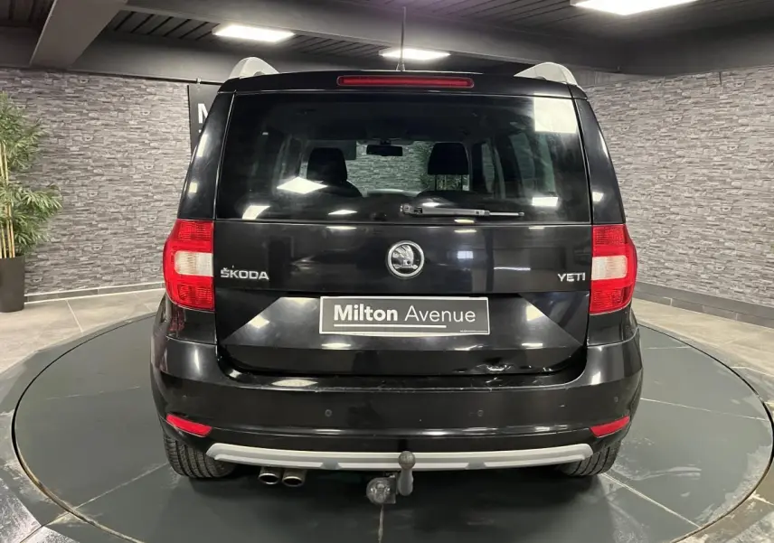 Vue arrière d'un Skoda Yeti noir 2015 avec attelage et double sortie d'échappement visible en intérieur showroom.