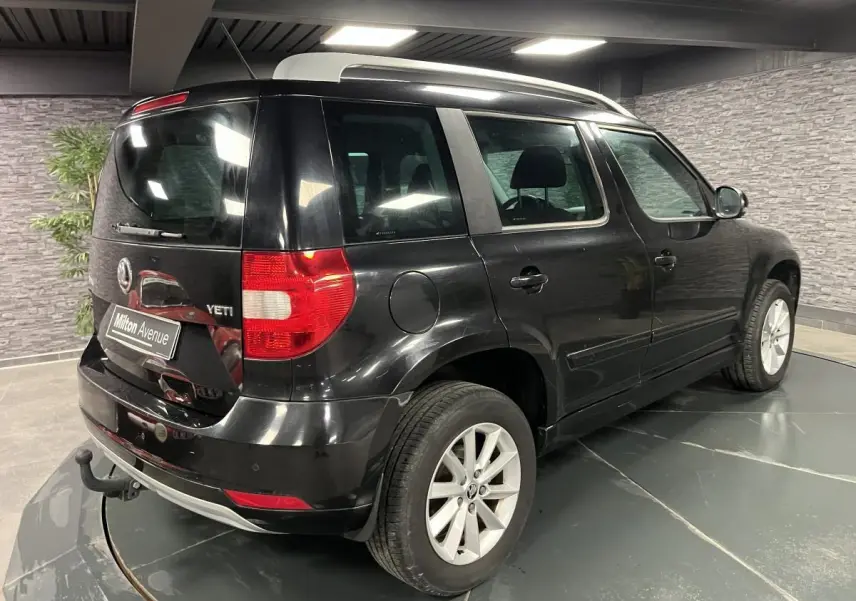 Vue 3/4 arrière droite d'un Skoda Yeti noir avec attelage et jantes alliage 16 pouces dans un showroom.