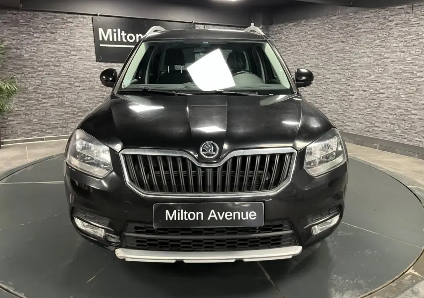 Vue frontale d'un Skoda Yeti noir avec calandre chromée et plaques "Milton Avenue" en intérieur showroom.