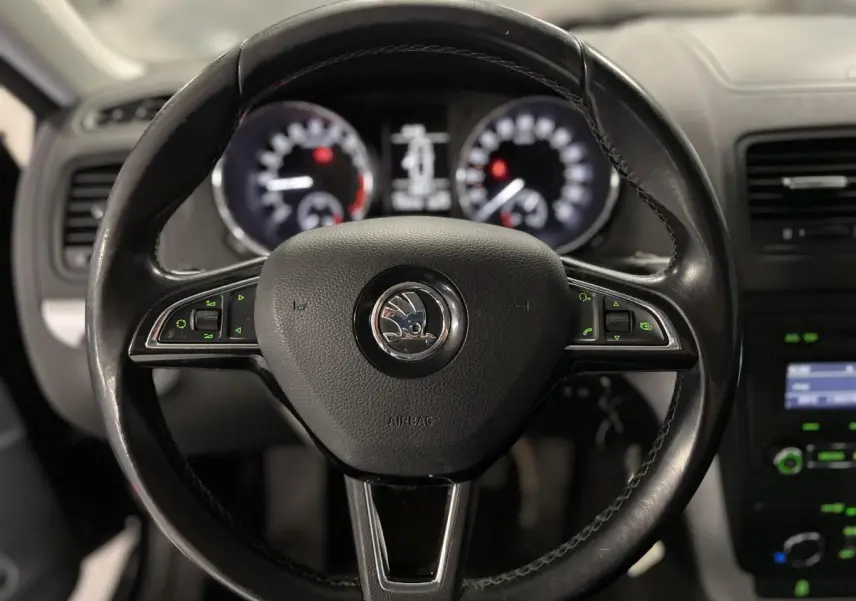 Volant cuir multifonctions noir de Skoda Yeti 2015 vu de face avec tableau de bord flou en arrière-plan.