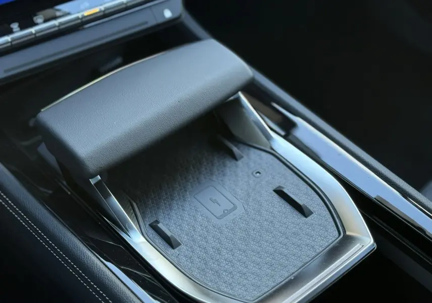 Gros plan sur la console centrale noire du Renault Espace VI 6 E-Tech avec chargeur smartphone à induction et accoudoir.