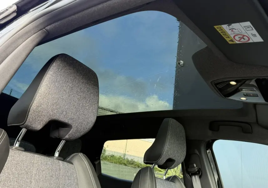Vue intérieure du toit panoramique en verre du Renault Espace VI avec appuie-têtes gris et ciel visible à travers.