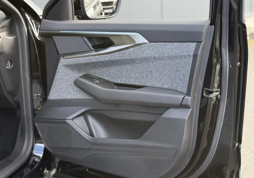 Gros plan sur la porte avant gauche du Renault Espace VI noir étoilé, avec insert tissu gris et poignée noire.