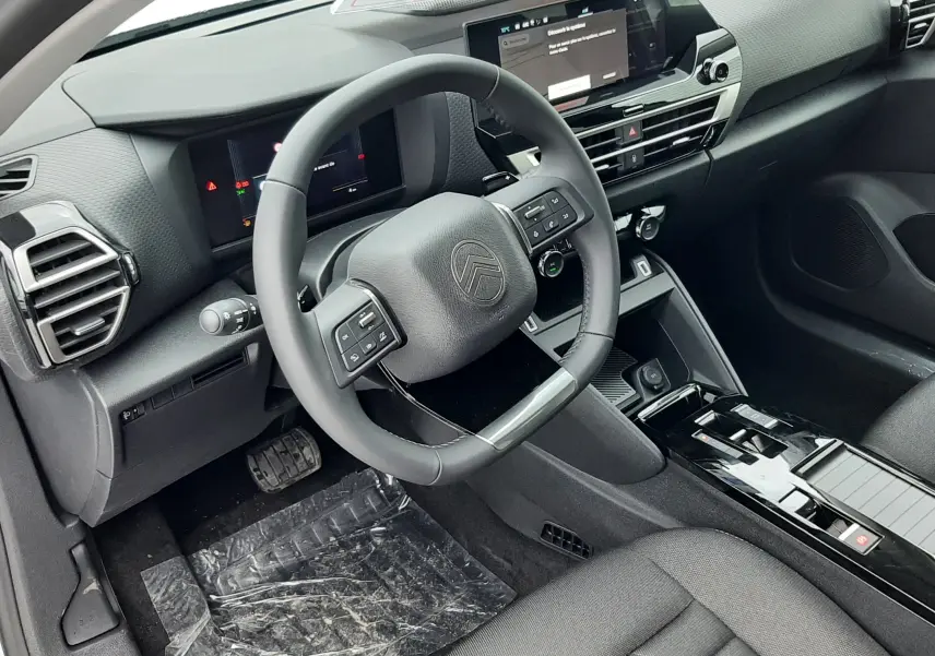 Intérieur du Citroën C4 1.2 Hybride 145ch Collection 2025, vue côté conducteur sur le tableau de bord et volant noir.