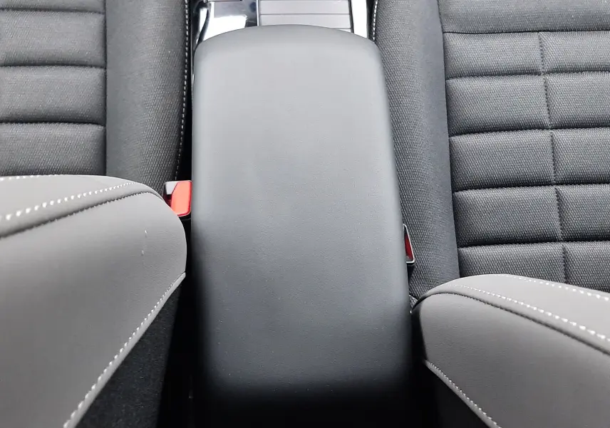 Vue rapprochée de l'accoudoir central et des sièges noirs en tissu de la Citroën C4 hybride 2025.