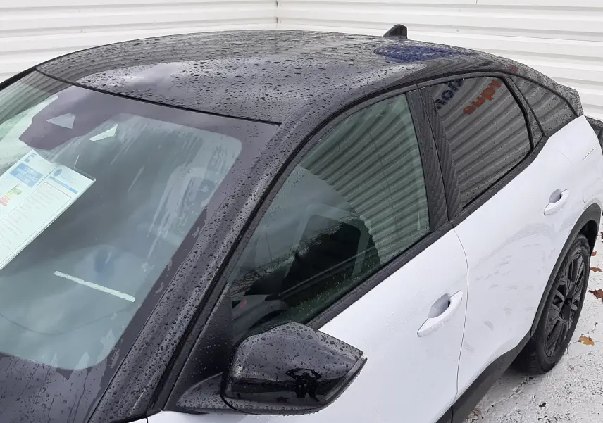 Vue de côté gauche avant d'une Citroën C4 2025 blanche Okenite avec toit noir Perla et rétroviseur assorti.