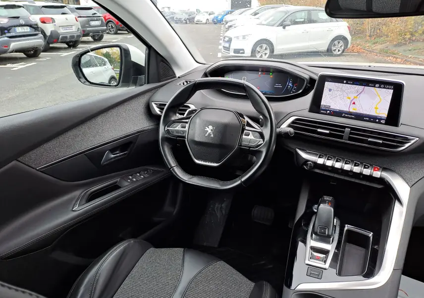 Intérieur du Peugeot 3008 blanc vu côté conducteur, volant compact, écran tactile avec GPS et commandes modernes.