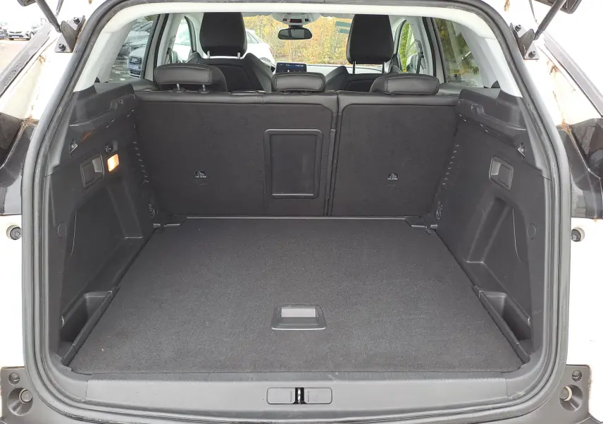 Coffre ouvert vu de l'arrière d'un Peugeot 3008 blanc, montrant un espace de chargement propre et spacieux.