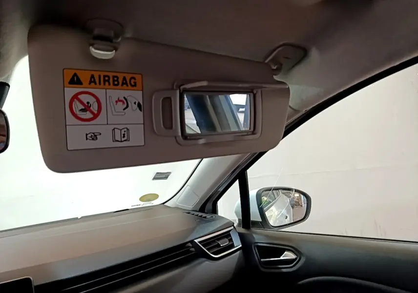 Détail intérieur côté passager de la Renault Clio blanche 2020, avec pare-soleil ouvert et miroir visible.