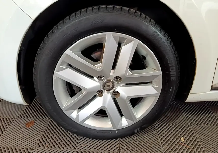 Gros plan sur la roue avant gauche blanche d'une Renault Clio Business Blue dCi 85 avec jante alliage moderne.