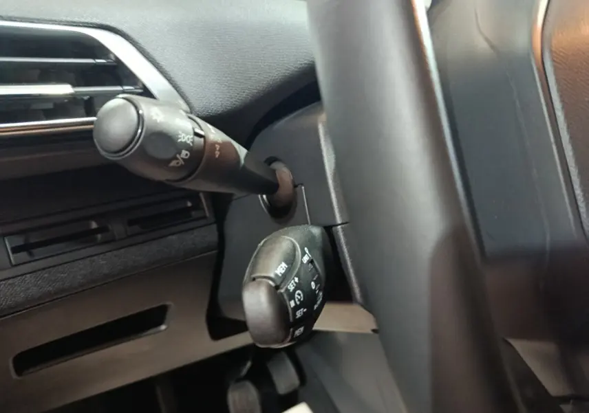 Gros plan sur les commandes au volant noir du Peugeot 3008 2020 BlueHDi, avec levier de clignotants et régulateur de vitesse.