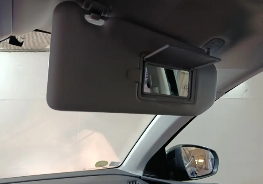 Miroir de courtoisie ouvert sur pare-soleil côté conducteur dans l'habitacle clair d'un Peugeot 3008 2020.