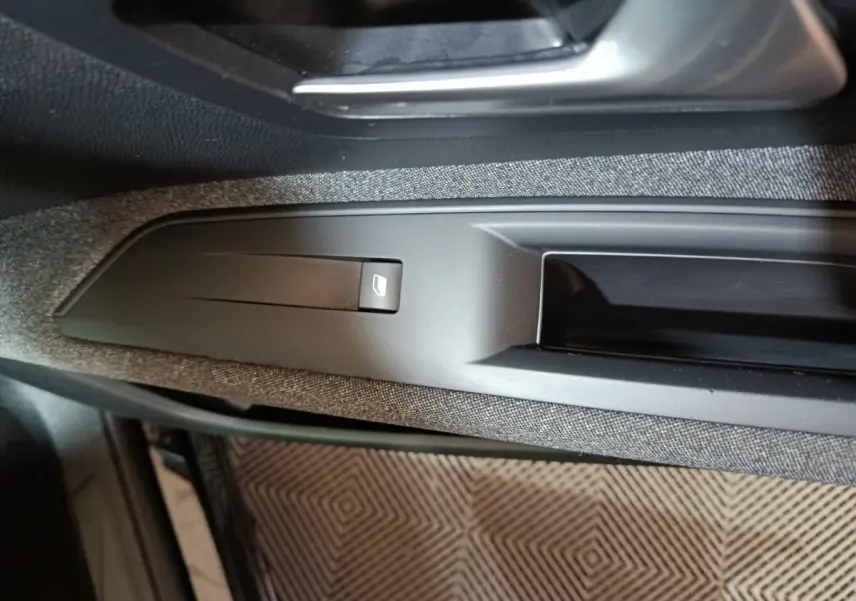 Gros plan sur la commande de lève-vitre côté conducteur du Peugeot 3008 2020, intérieur noir et tissu gris.