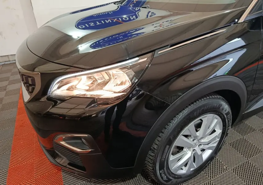Gros plan sur l'avant droit noir brillant du Peugeot 3008 avec phare allumé et jante alu visible.