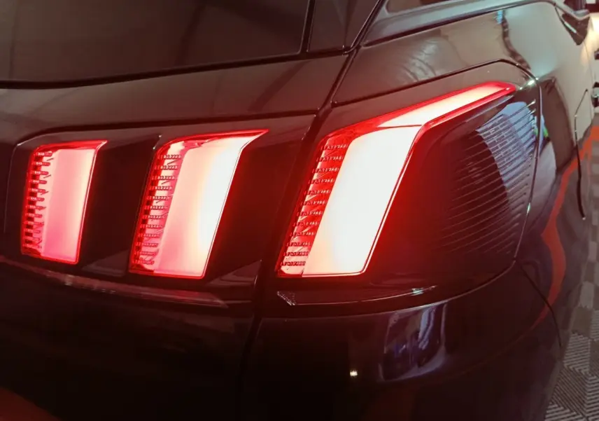 Gros plan sur les feux arrière droits rouges allumés d’un Peugeot 3008 2020 couleur foncée.