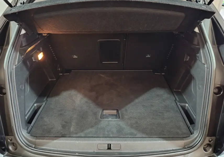 Coffre ouvert vu de l'arrière d'un Peugeot 3008 2020, intérieur noir avec éclairage latéral à gauche.