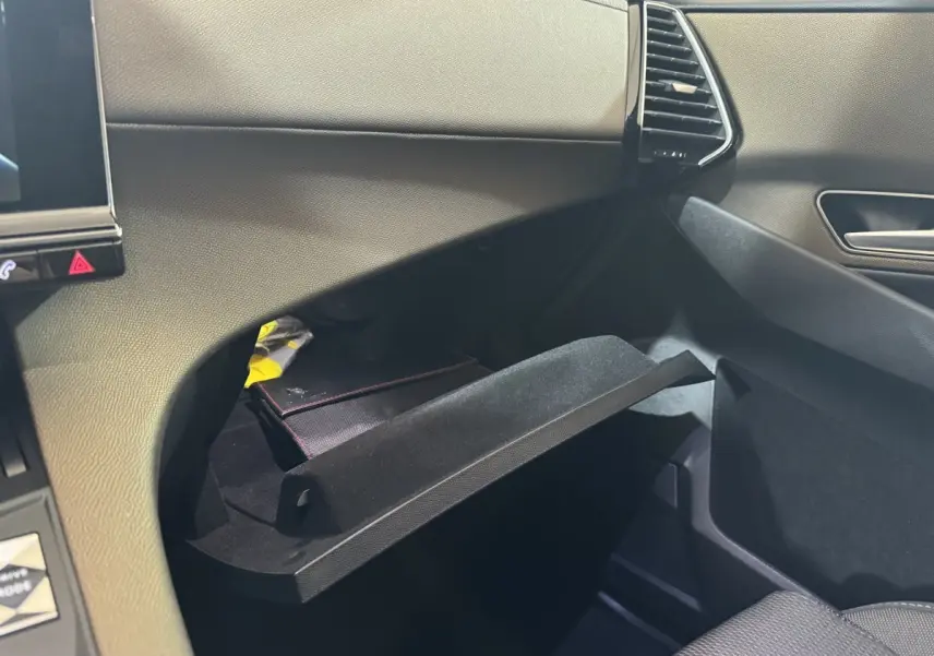 Intérieur de la DS7 Crossback E-TENSE 225 Bastille+, vue sur la boîte à gants ouverte côté passager, finition gris foncé.