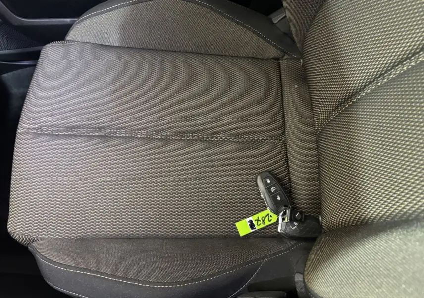 Gros plan sur la sellerie tissu gris foncé du siège avant droit avec clé de voiture posée dessus.